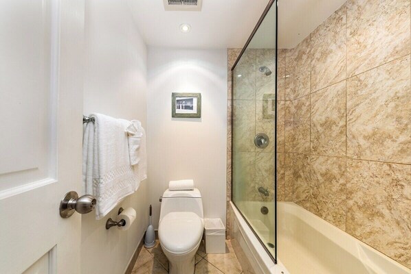Un baño con ducha de vidrio, inodoro y lavabo.