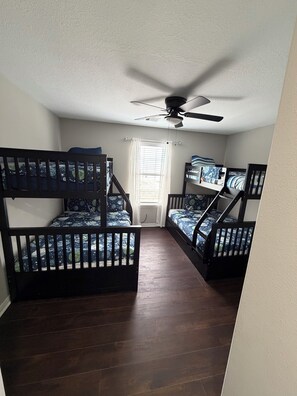 A room with two bunk beds, a ceiling fan, and a window with blinds. - Comfortable and safe family lodging for everyone close to the medical center.  (Houston)