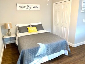 Une chambre à coucher avec un lit, une table de chevet, une lampe et une porte.