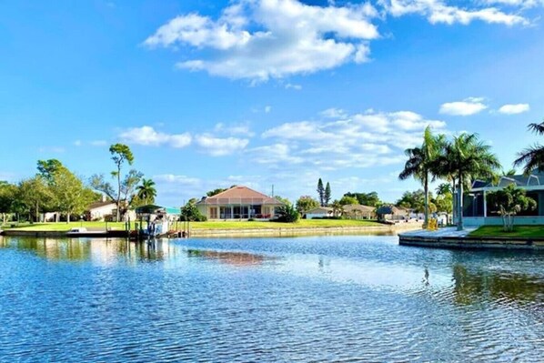 Una propiedad frente al agua con un edificio grande, un lago tranquilo y abundante vegetación.