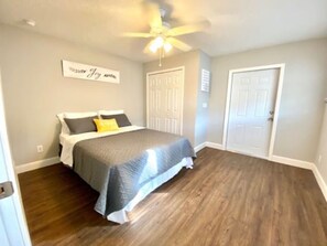 Un dormitorio con cama, ventilador de techo y puerta.