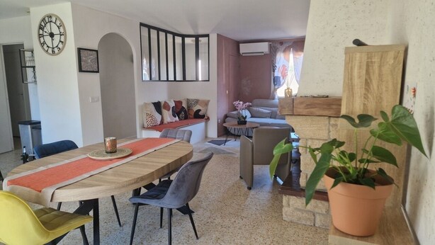 A dining area with a wooden table, chairs, and a potted plant.