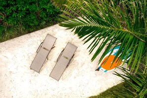 Zandgebied met twee ligbedden en een strandbal.