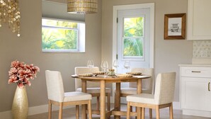 A dining area with a round wooden table, four chairs, and a vase of flowers. - `The Morning Star` w/ spa & Private Mini Beach (Naples)