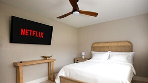 A bedroom with a bed, a bedside table, a nightstand, a ceiling fan, and a wall-mounted TV displaying the Netflix logo. - `The Morning Star` w/ spa & Private Mini Beach (Naples)