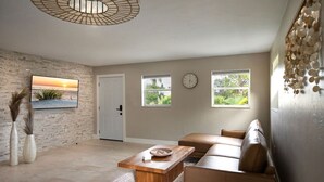 A spacious living room with a large window, a wooden coffee table, a sofa, and a door. - `The Morning Star` w/ spa & Private Mini Beach (Naples)