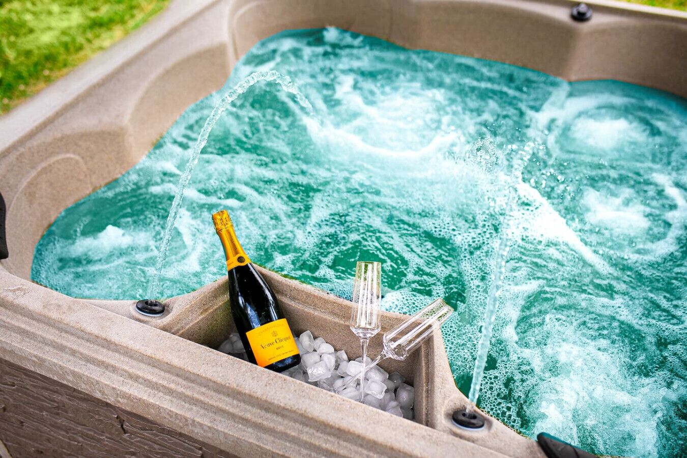 A hot tub with a bottle of champagne and two glasses.