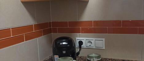 Una cocina con una cafetera, una taza y un tarro sobre la encimera.