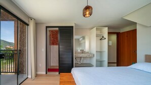 Een moderne slaapkamer met een groot bed, een houten vloer, een glazen schuifdeur naar een balkon en een hanglamp.