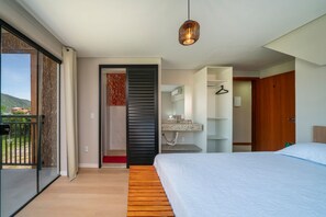 Een moderne slaapkamer met een groot bed, een houten vloer, een glazen schuifdeur naar een balkon en een hanglamp.