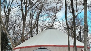 A yurt with a wooden deck and a covered outdoor seating area.