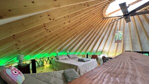 A cozy, well-lit tent with a bed, pillows, and a small table.