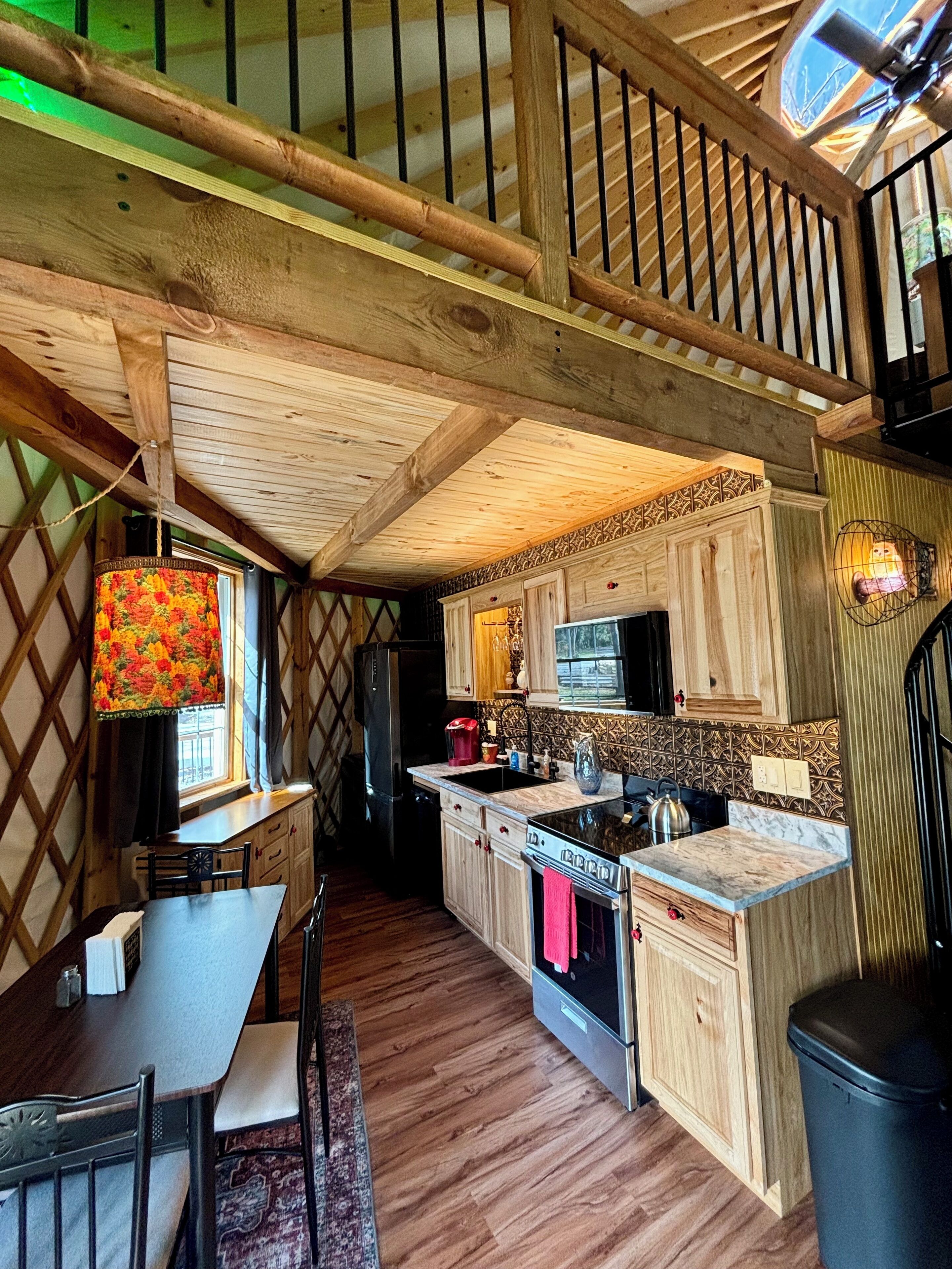 A cozy kitchen with wooden cabinets, a stove, and a dining area with a table and chairs.