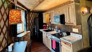 A cozy kitchen with wooden cabinets, a stove, and a dining area with a table and chairs.