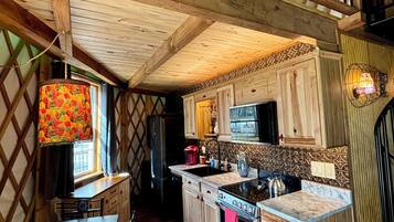 A cozy kitchen with wooden cabinets, a stove, and a dining area with a table and chairs.