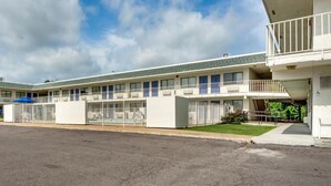 A motel with a central corridor, individual rooms on either side, and a covered parking area. - AVERA SUITES (Muskogee)