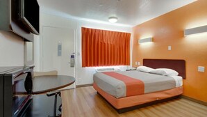 A hotel room with a bed, a desk, and a television. - AVERA SUITES (Muskogee)