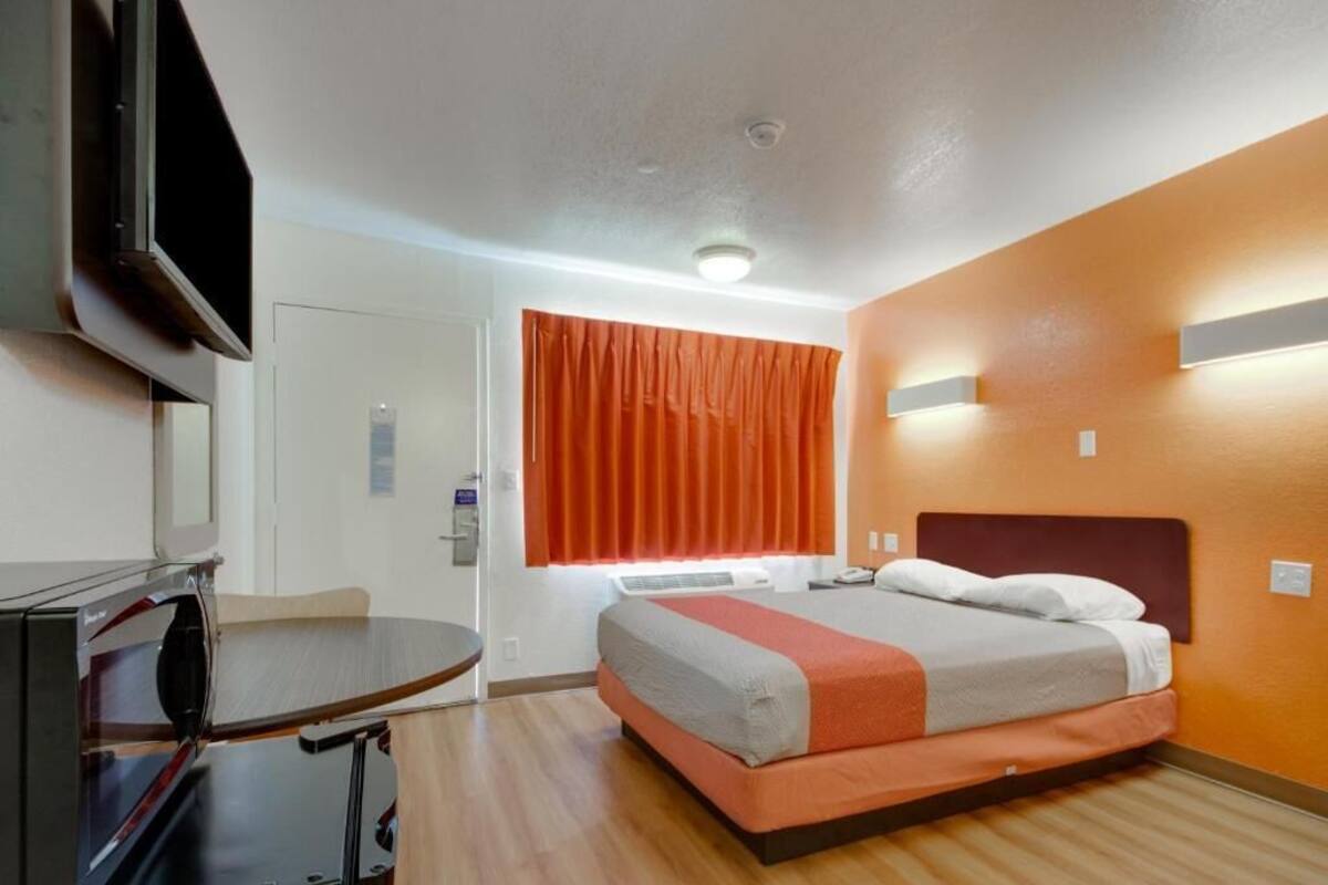 Ein Hotelzimmer mit Bett, Schreibtisch und Fernseher.