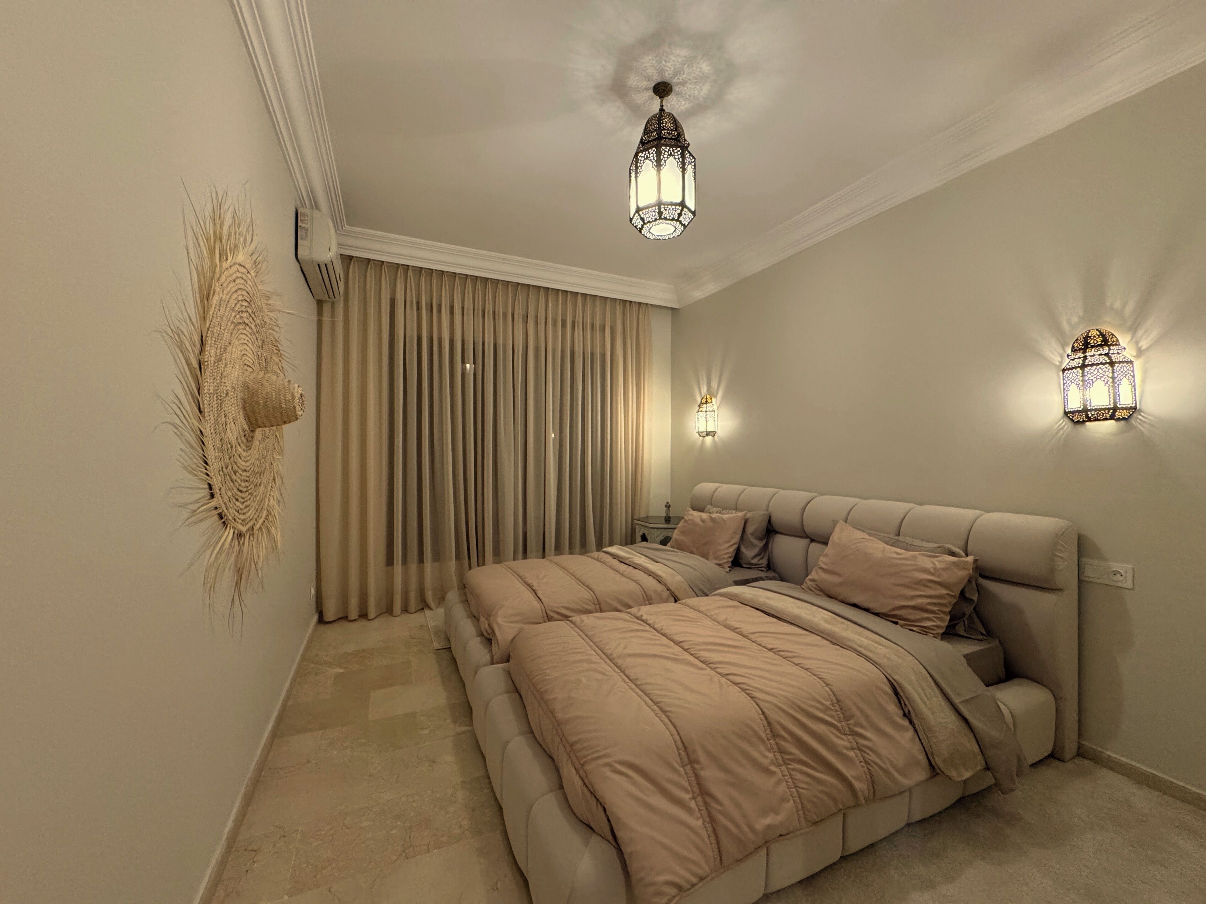 Een slaapkamer met een groot bed, twee wandlampen en een decoratief kunstwerk.