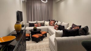 Ein modernes Wohnzimmer mit einem Ecksofa, einem Couchtisch und einem an der Wand montierten Fernseher.