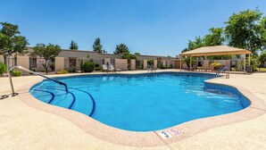 A swimming pool with a safety sign, lounge chairs, and a covered seating area. - 3BR Southwest Modern Haven - Old Town (Scottsdale)
