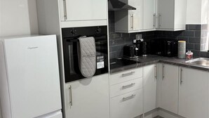 A modern kitchen with white cabinets, a black countertop, and a stainless steel sink. - Central Chelmsford 2-bed Apt, 5 Mins to Station (Chelmsford)