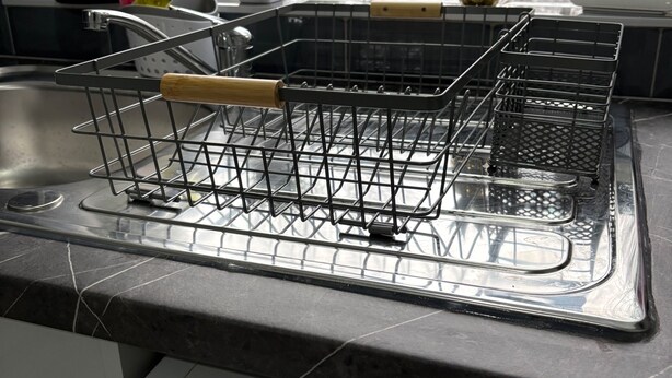 A kitchen with a dish rack on the counter, a washing machine, and a window with a view of a house and trees. - Central Chelmsford 2-bed Apt, 5 Mins to Station (Chelmsford)
