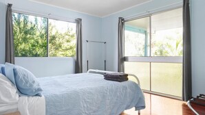 A bedroom with a bed, a window, and a balcony.