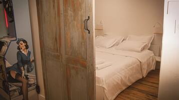 Une pièce avec un lit, un plancher en bois et une porte dotée d’une poignée en métal.