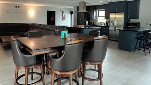 A spacious kitchen with dark cabinetry, a central island, and a dining area with a table and chairs. - Serene Getaway – Quiet Oasis with Pool & Rain Showers (Harlingen)