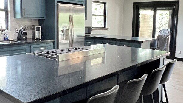A modern kitchen with a large island, stainless steel appliances, and bar stools. - Serene Getaway – Quiet Oasis with Pool & Rain Showers (Harlingen)