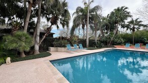 A swimming pool with lounge chairs and palm trees. - Serene Getaway – Quiet Oasis with Pool & Rain Showers (Harlingen)