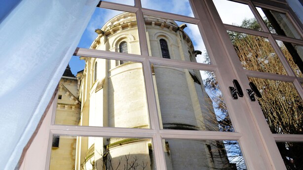Vista a través de una ventana que muestra un edificio con cúpula y ventanas de arco.