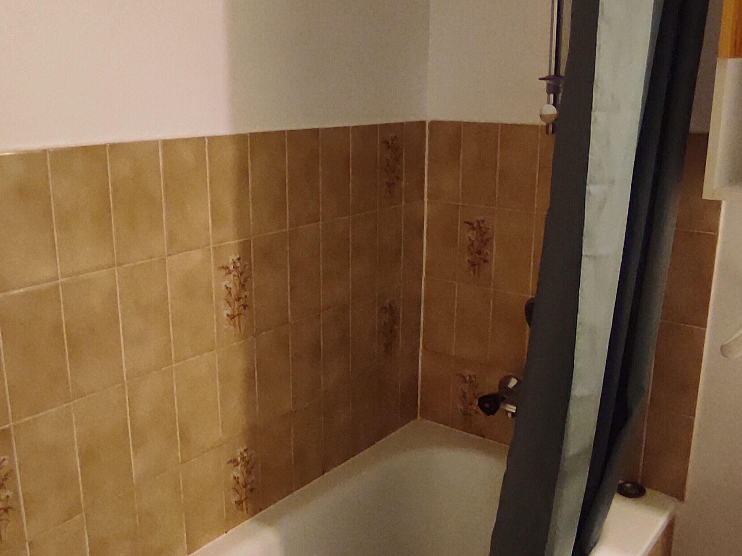 A bathroom with a bathtub, tiled walls, and a shower curtain.