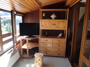 Un intérieur en bois avec une télévision, un bureau et un meuble avec des tiroirs.