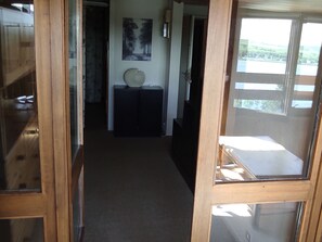A corridor with a wooden door frame, a dark-colored cabinet, and a painting on the wall.