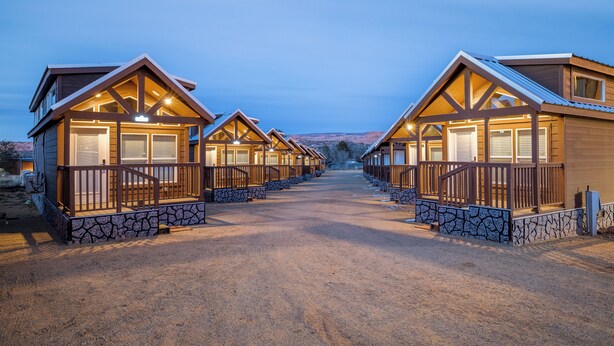 A row of wooden cabins with stone foundations, each featuring a porch and large windows. - Arches Hut (Moab)