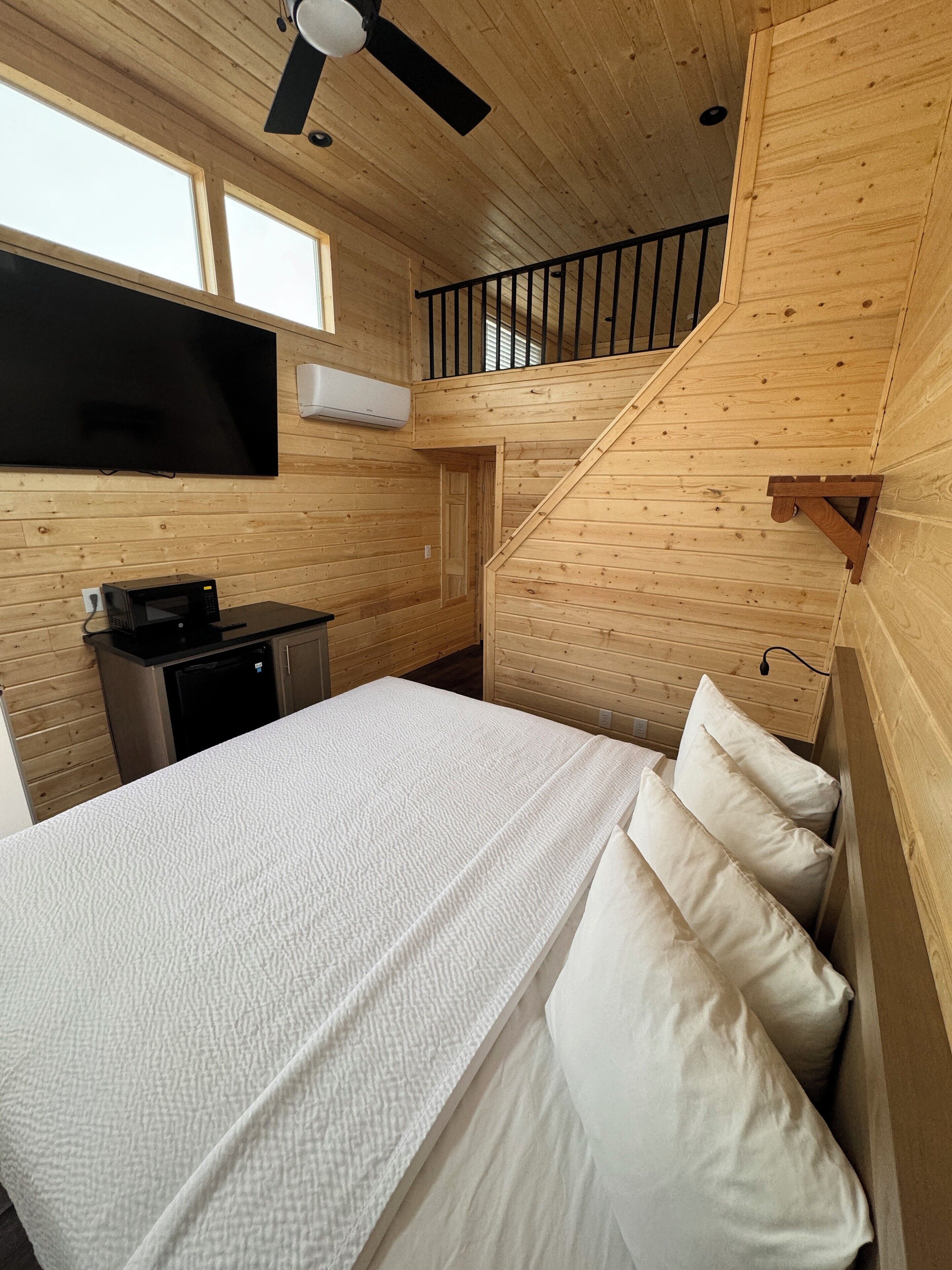 Une chambre dans un chalet en bois, équipée d’un lit, d’une télévision et d’un four à micro-ondes.