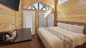 A wooden cabin room with a bed, a desk, and a TV. - Arches Hut (Moab)