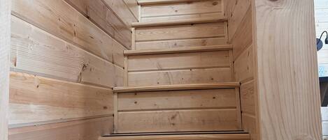 A wooden staircase with a handrail, leading to a higher level.