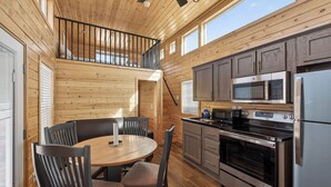 A wooden cabin interior with a dining area, kitchen, and a balcony. - Arches Hut (Moab)