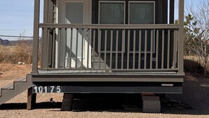 A small, single-story cabin with a balcony, a front door, and a mailbox. - Arches Hut (Moab)