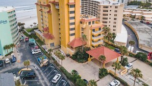 Ein mehrstöckiges Hotel mit Innenhof, Parkplatz und Blick auf den Strand.