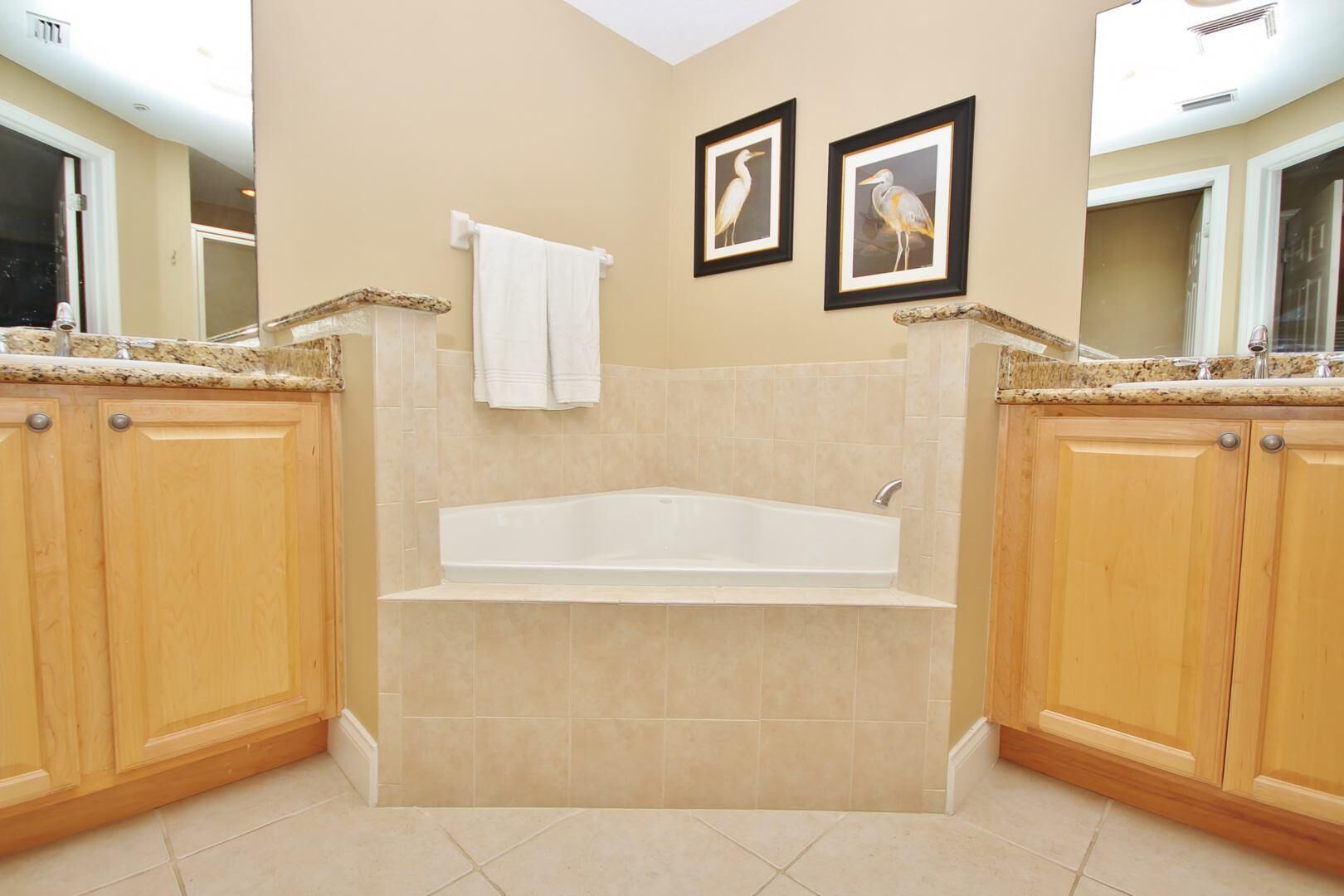 A bathroom with a freestanding bathtub, wooden cabinets, and two framed pictures on the wall.