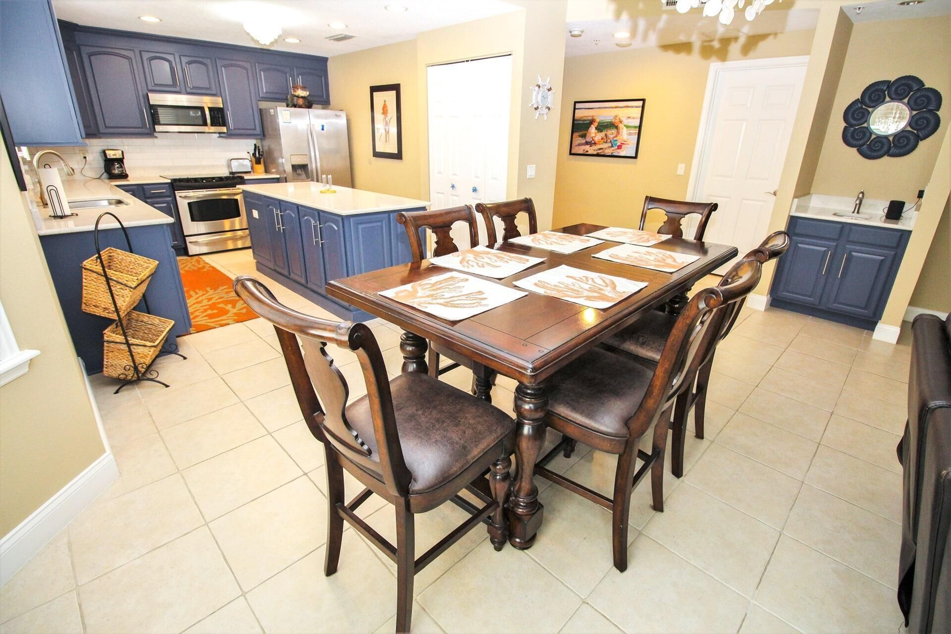 A kitchen with blue cabinets, a dining table with six chairs, and a refrigerator.