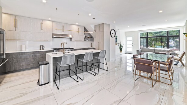 Una cocina moderna con una isla central, taburetes de bar y una mesa de comedor con sillas.