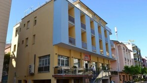 Un immeuble à plusieurs étages, doté d’une façade jaune, de nombreux balcons et d’un escalier menant à l’entrée.