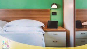 Une chambre d’hôtel avec un lit, deux tables de chevet, un ordinateur portable et une petite table de nuit avec une lampe.