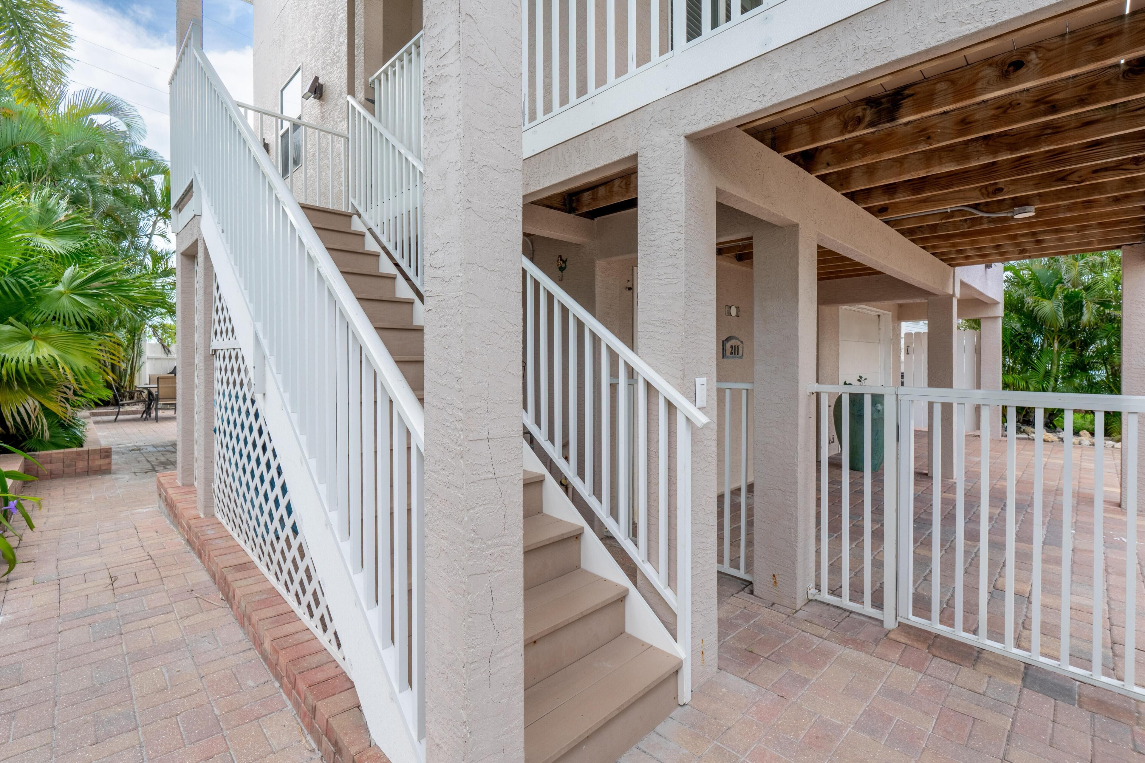 Un bâtiment à plusieurs niveaux, doté d’un escalier, d’un espace extérieur aménagé pour s’asseoir et d’une terrasse couverte.
