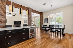 A modern kitchen with a large island, wooden flooring, and pendant lighting.